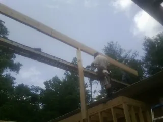 Carpenter setting a ridge beam over a new addition frame — Ice Dam Removal by Roofing Brothers in Brownsville