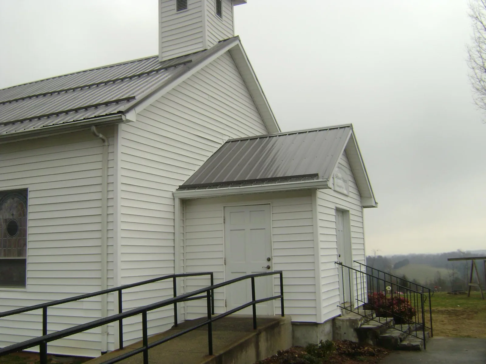 Gray metal roof on a white clapboard church with a steeple in Brownsville